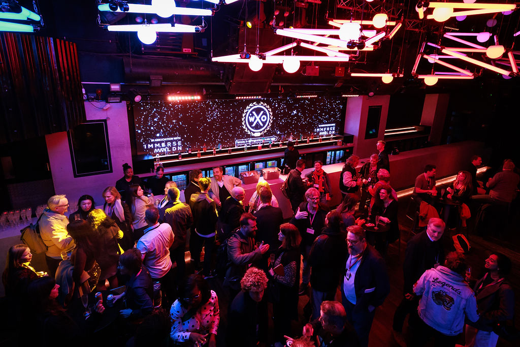 Attendees networking under the branded screen at London Experience Week